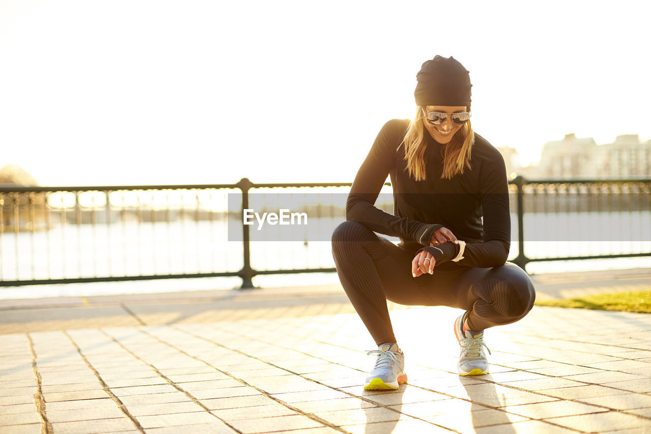 A backlit outdoor portrait of a woman checking her smart watch.