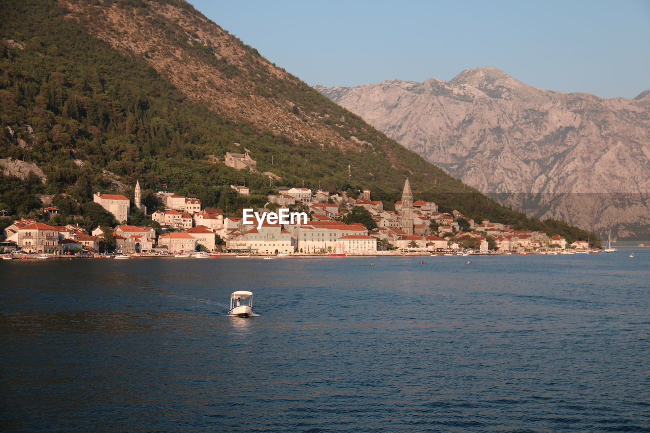 Scenic view of sea by townscape against sky