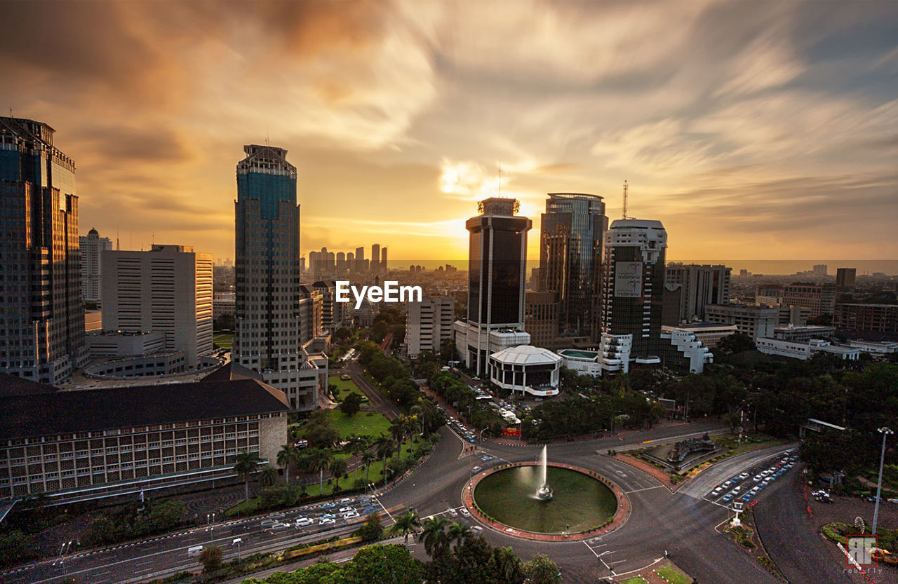 Cityscape against cloudy sky during sunset