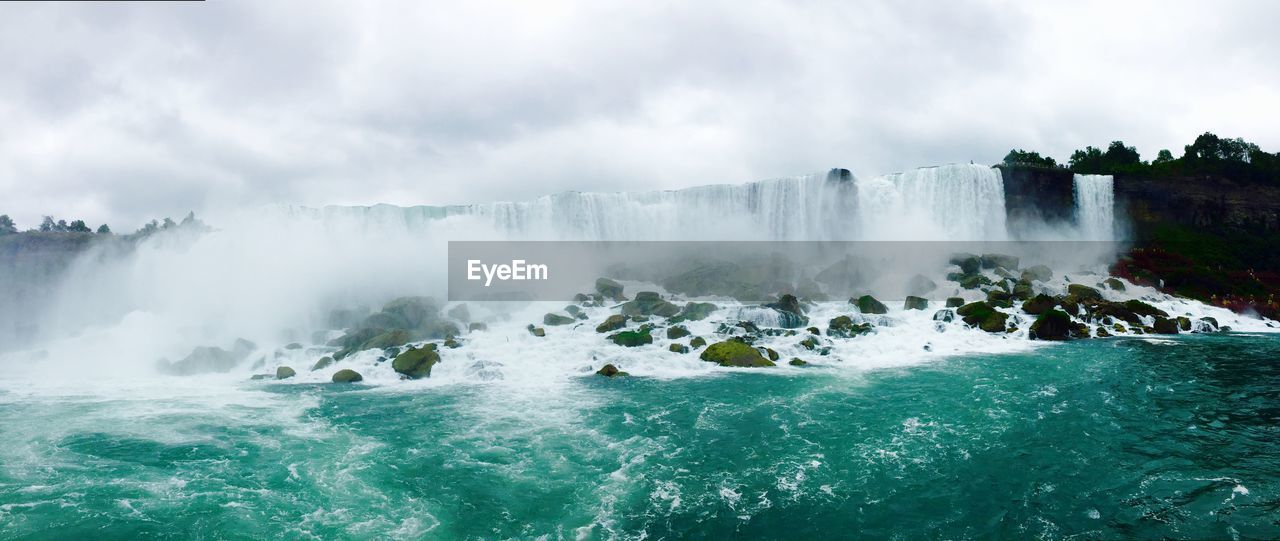 Panoramic view of waterfall against cloudy sky