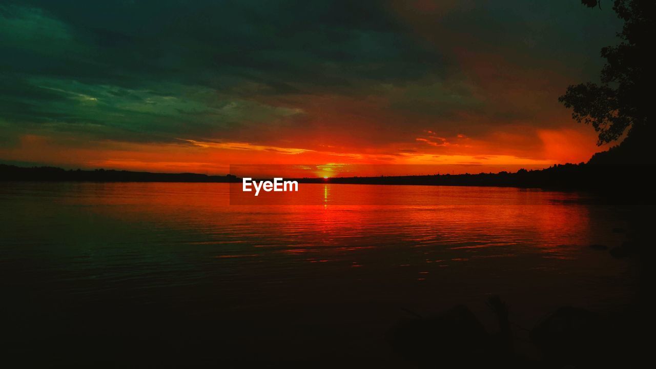 SCENIC VIEW OF LAKE AGAINST DRAMATIC SKY DURING SUNSET