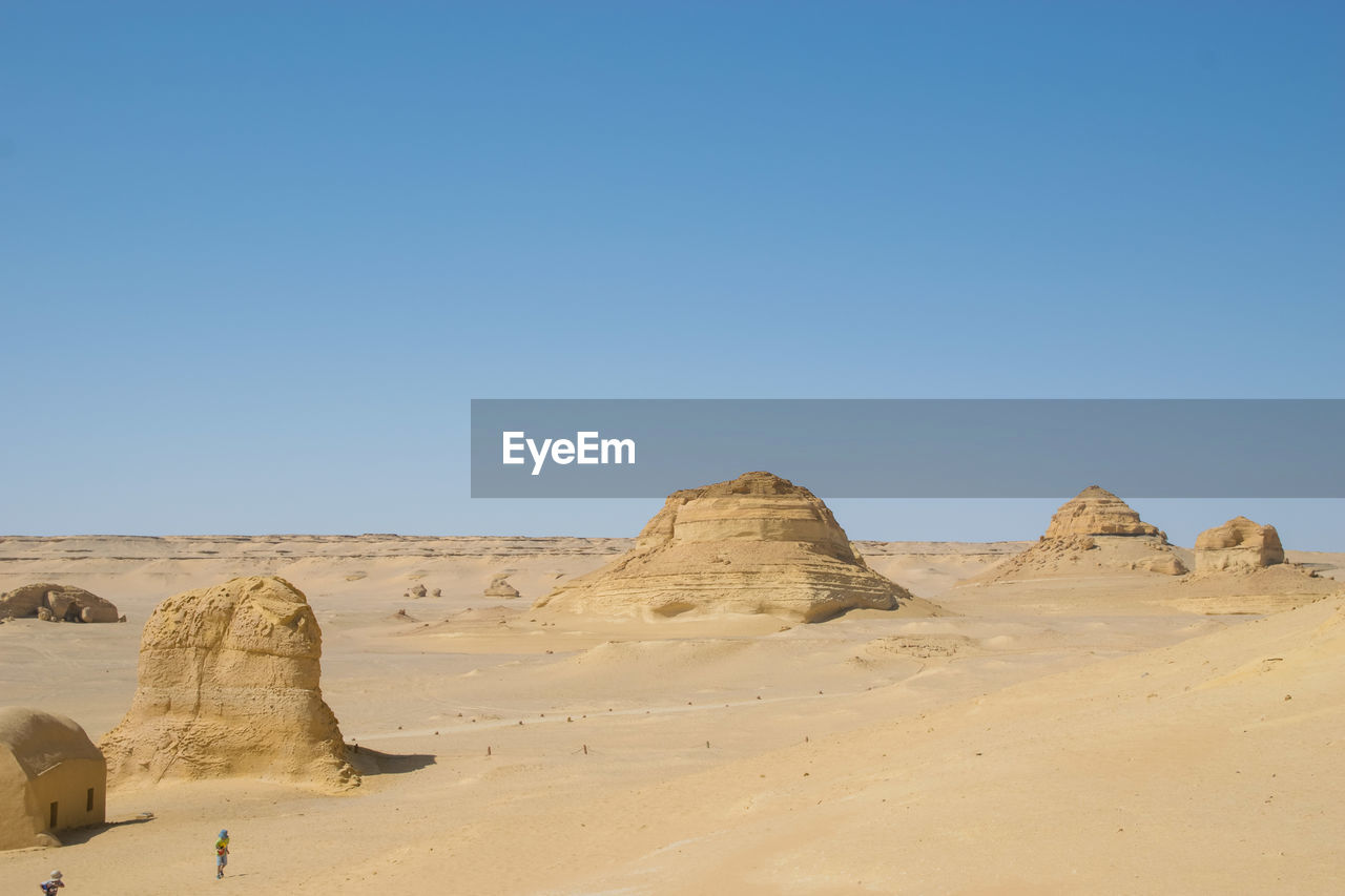 Rock formations in desert against clear blue sky during sunny day