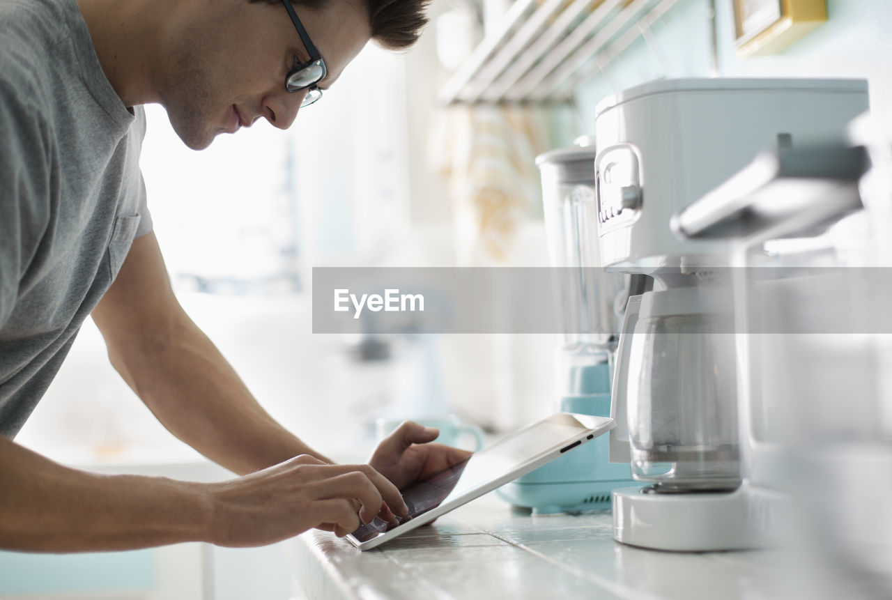 Man using tablet while standing at kitchen counter