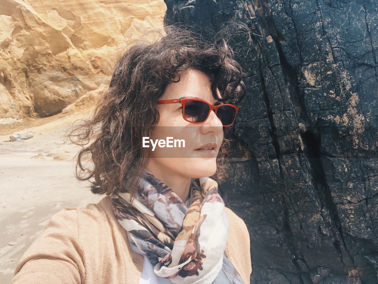 Woman wearing sunglasses against rock formation