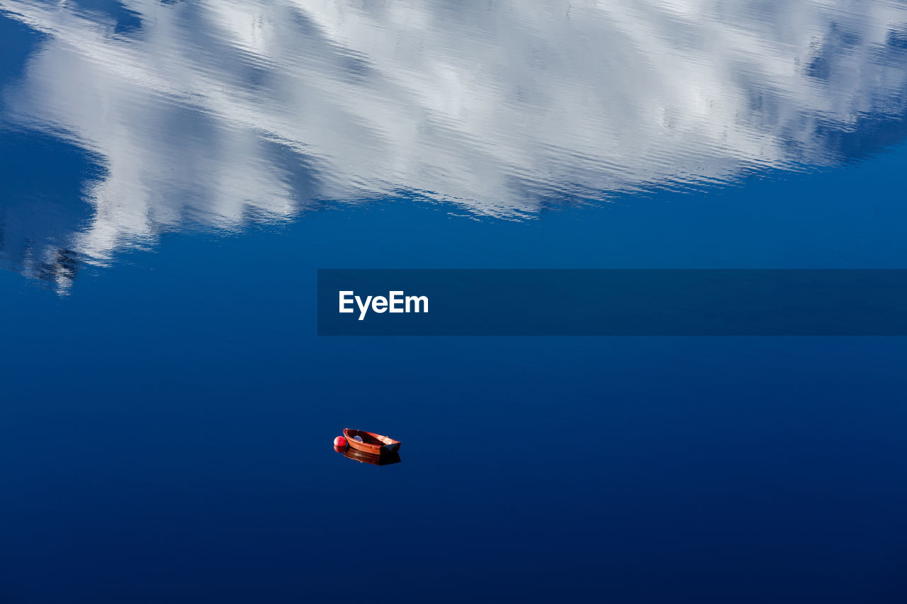 High angle view of boat moored in lake with reflection of cloud