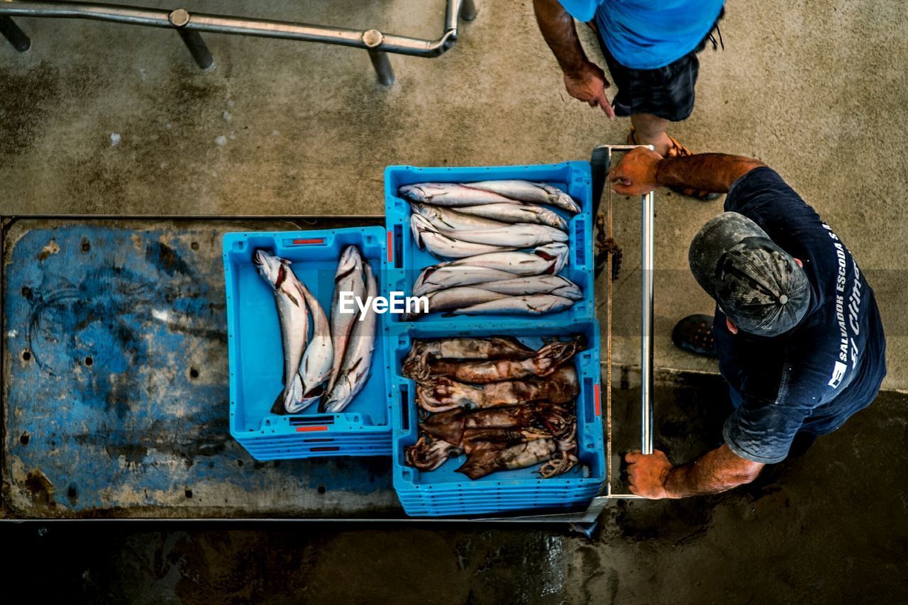 Fish market worker carrying cases from above