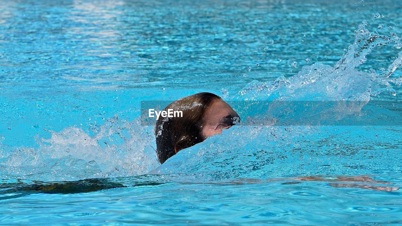 Woman swimming in pool on sunny day