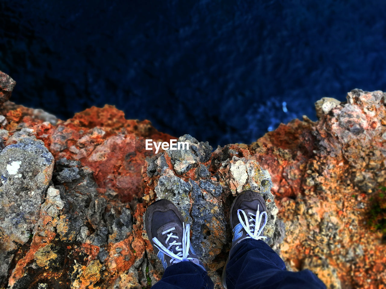 LOW SECTION OF PERSON STANDING ON ROCK BY ROCKS