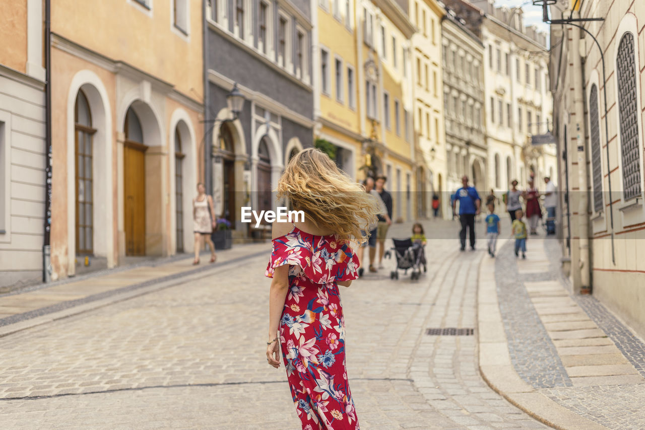 Rear view of woman standing on street in city