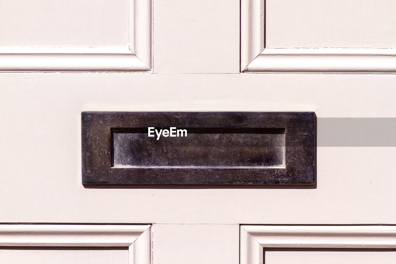 Olished steel letterbox on a white wooden front door