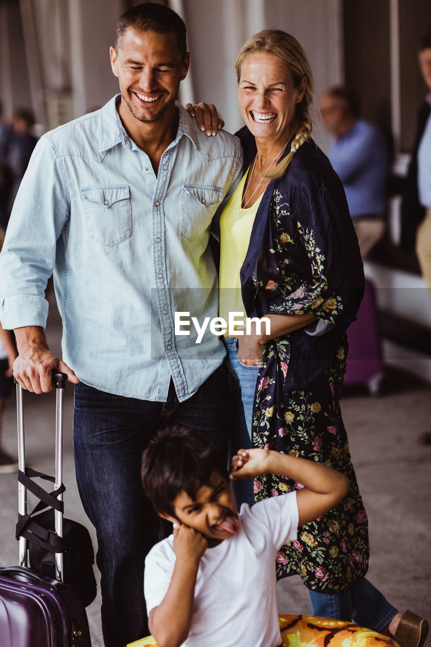 Cheerful parents enjoying with son making face while waiting at railroad station