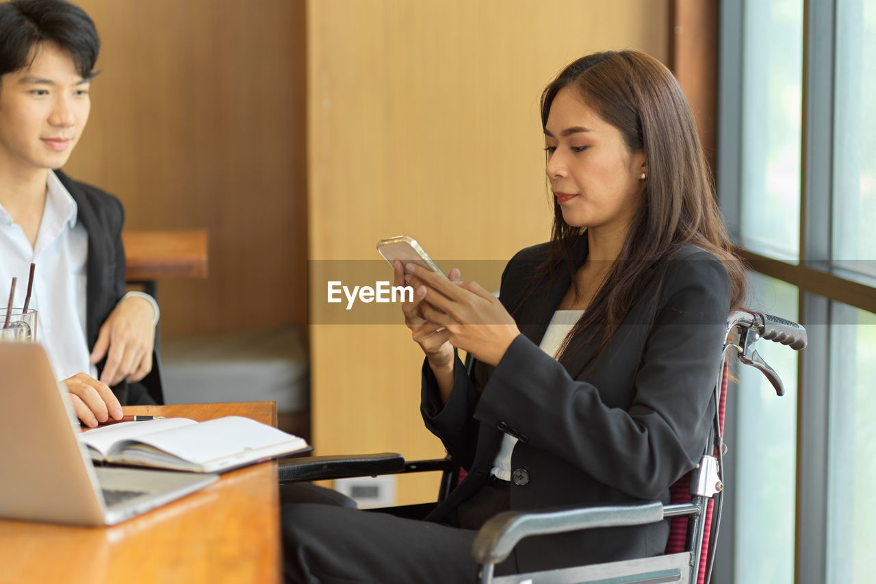 Young woman using phone while sitting on table