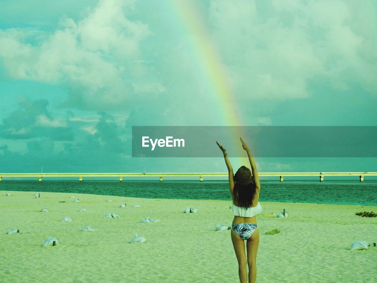 Rear view of woman standing against rainbow at beach