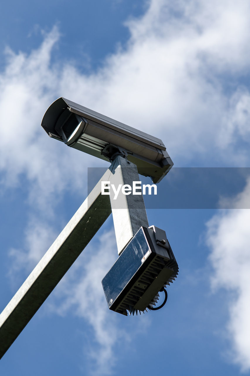 Low angle view of security camera against cloudy sky