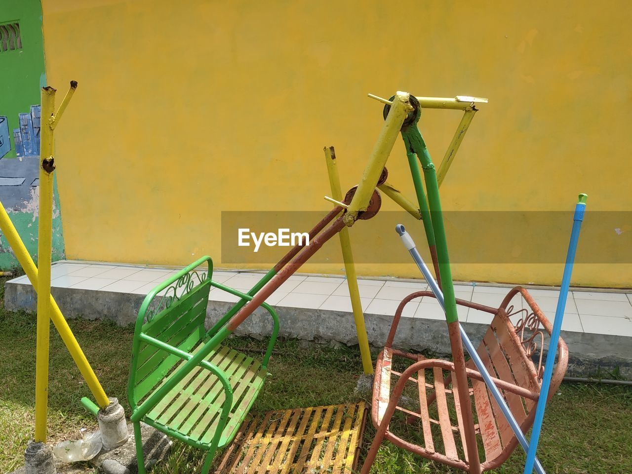 no people, day, nature, vehicle, playground, outdoor play equipment, metal, green, wall - building feature, yellow, architecture, outdoors, bicycle, grass, absence, seat, built structure, chair