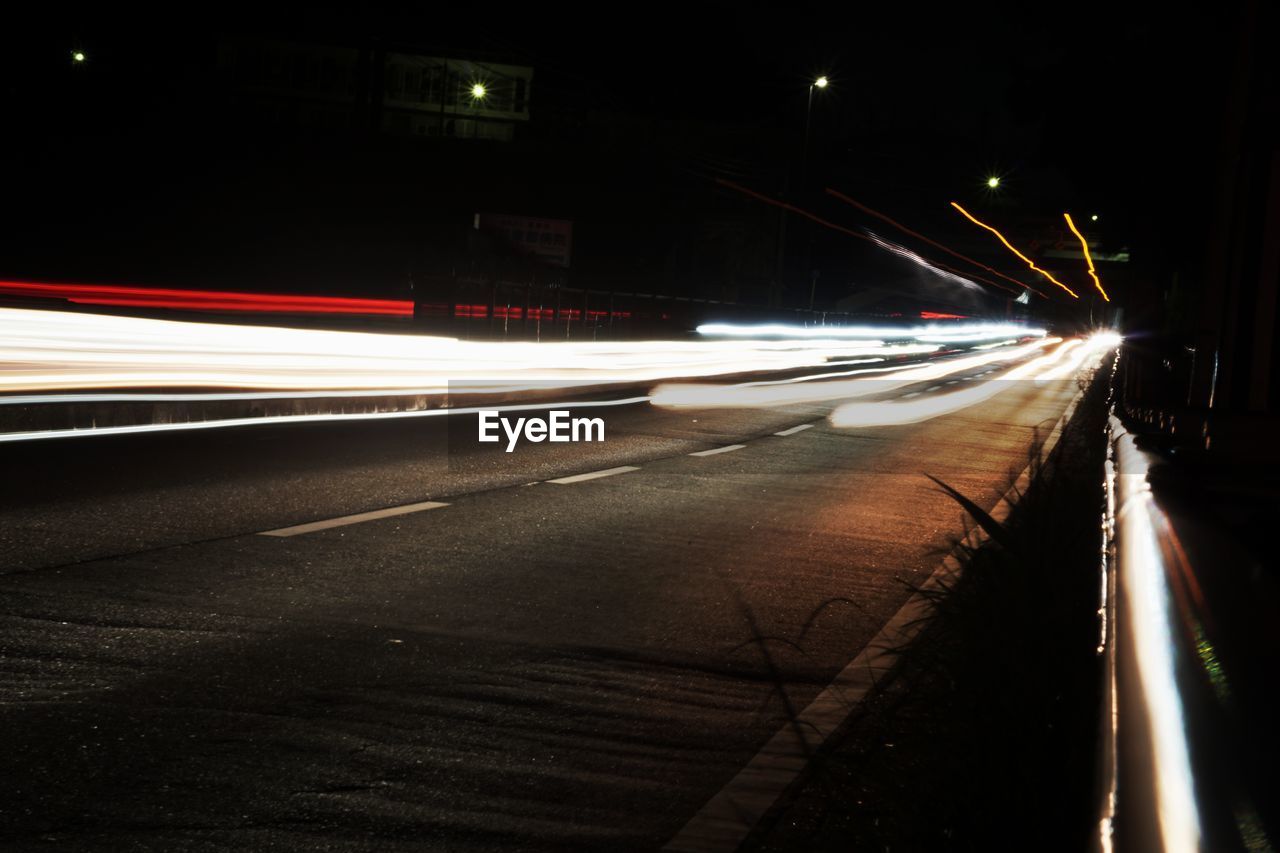 ILLUMINATED LIGHT TRAILS ON ROAD AT NIGHT