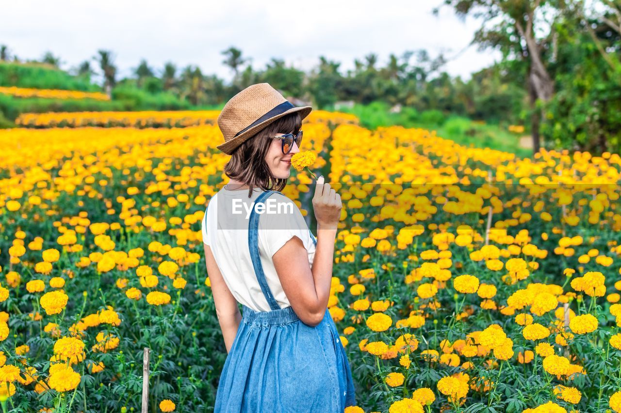 Woman standing amidst flowering plants on field