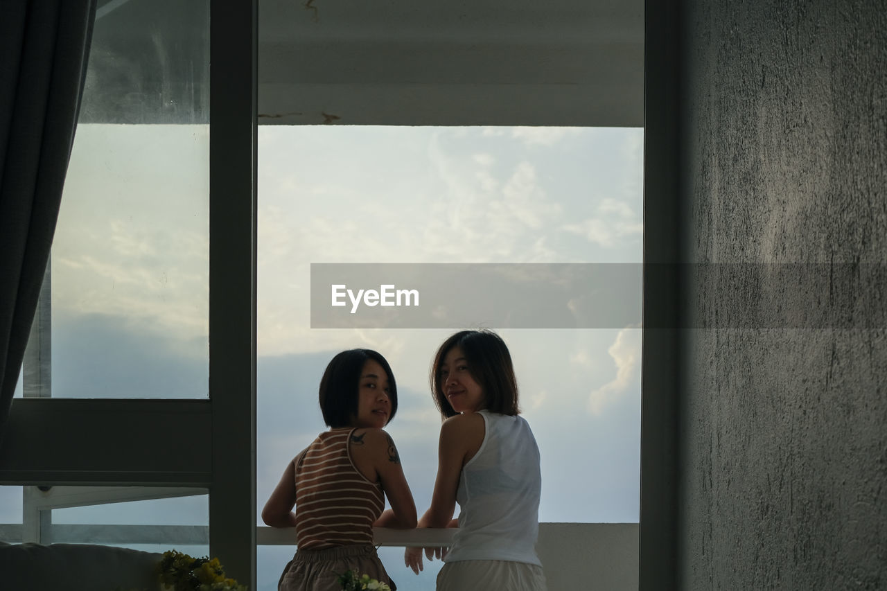 rear view of woman looking through window at home