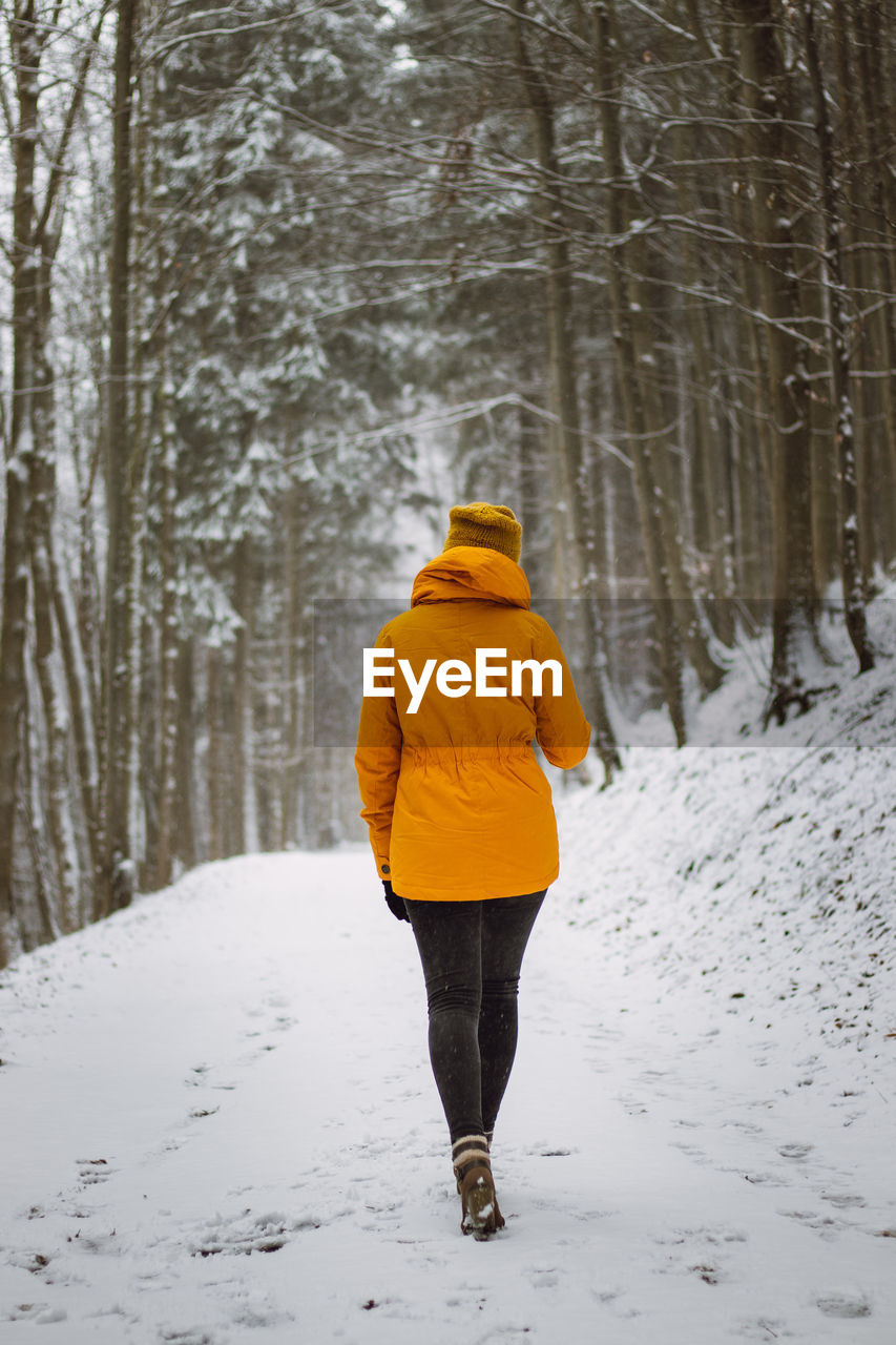 Rear view of woman walking on snow covered land