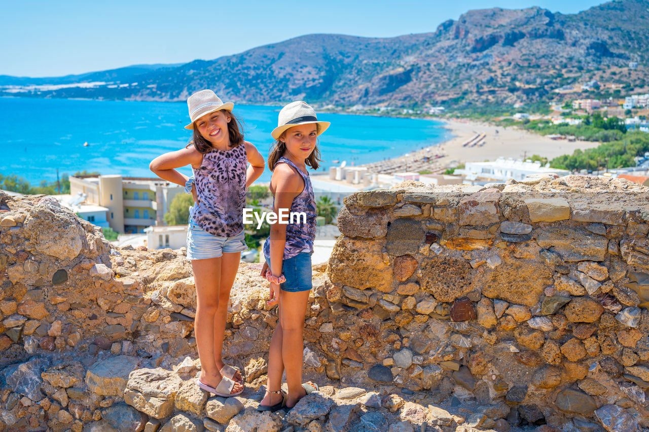 full length of young woman standing on rock at beach