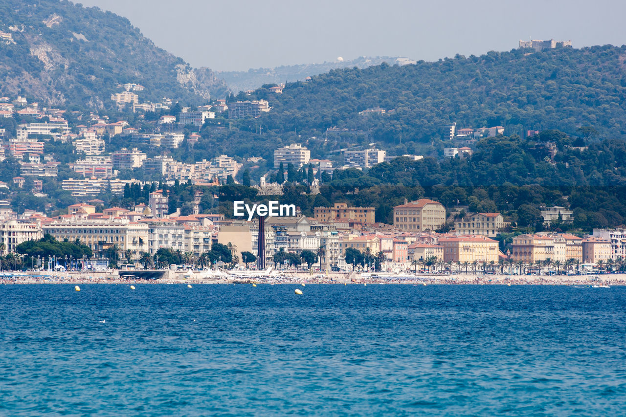 BUILDINGS BY SEA AGAINST SKY IN CITY