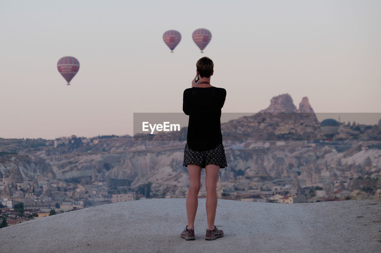 Rear view of woman standing on rock against sky