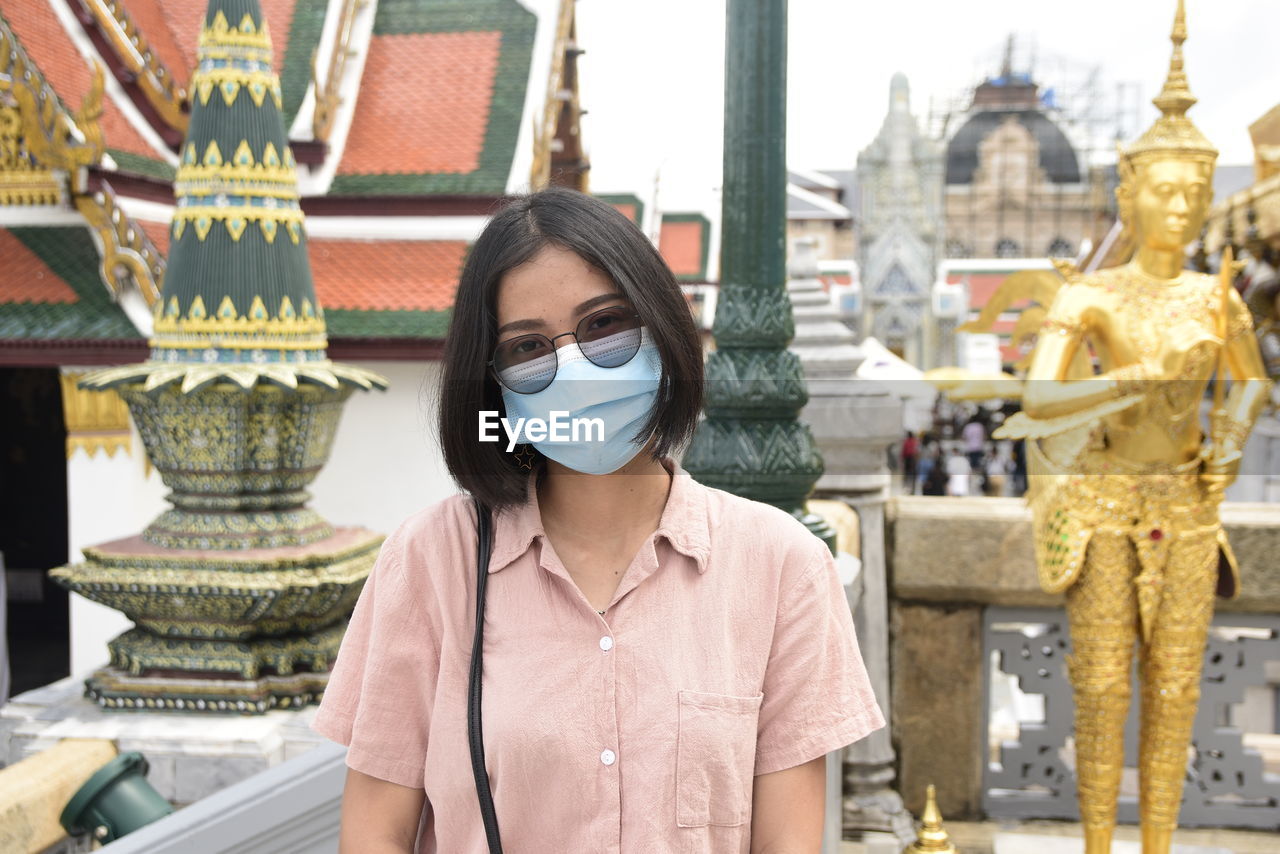 An asian woman standing at a thai temple and sculptures of thailand