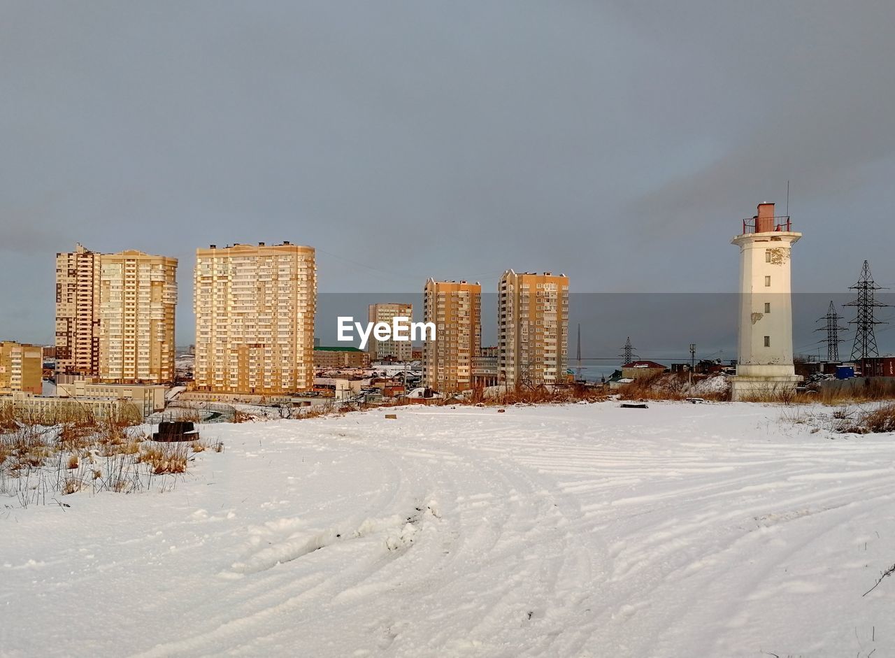 SNOW COVERED LAND AND BUILDINGS AGAINST SKY