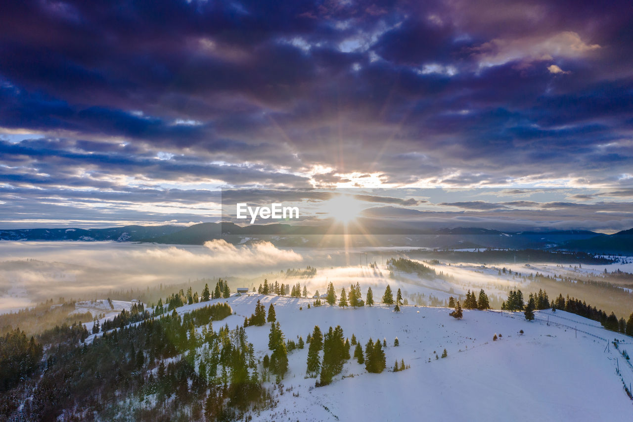 PANORAMIC VIEW OF SNOWCAPPED LANDSCAPE AGAINST SKY DURING SUNSET