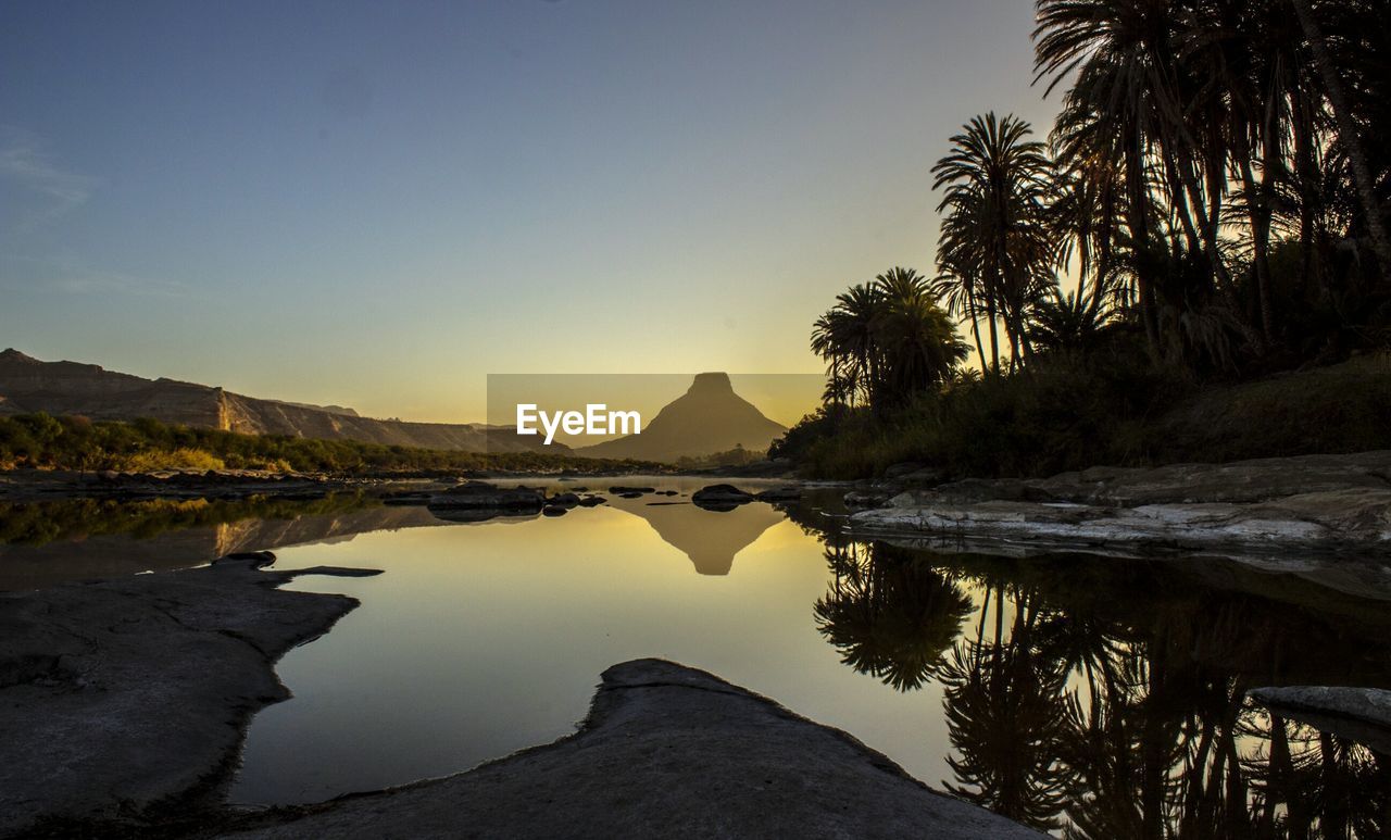 Scenic view of lake with mountain reflection against sky during sunset