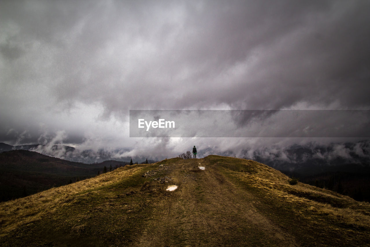 Hiker standing on dry grass hill landscape photo