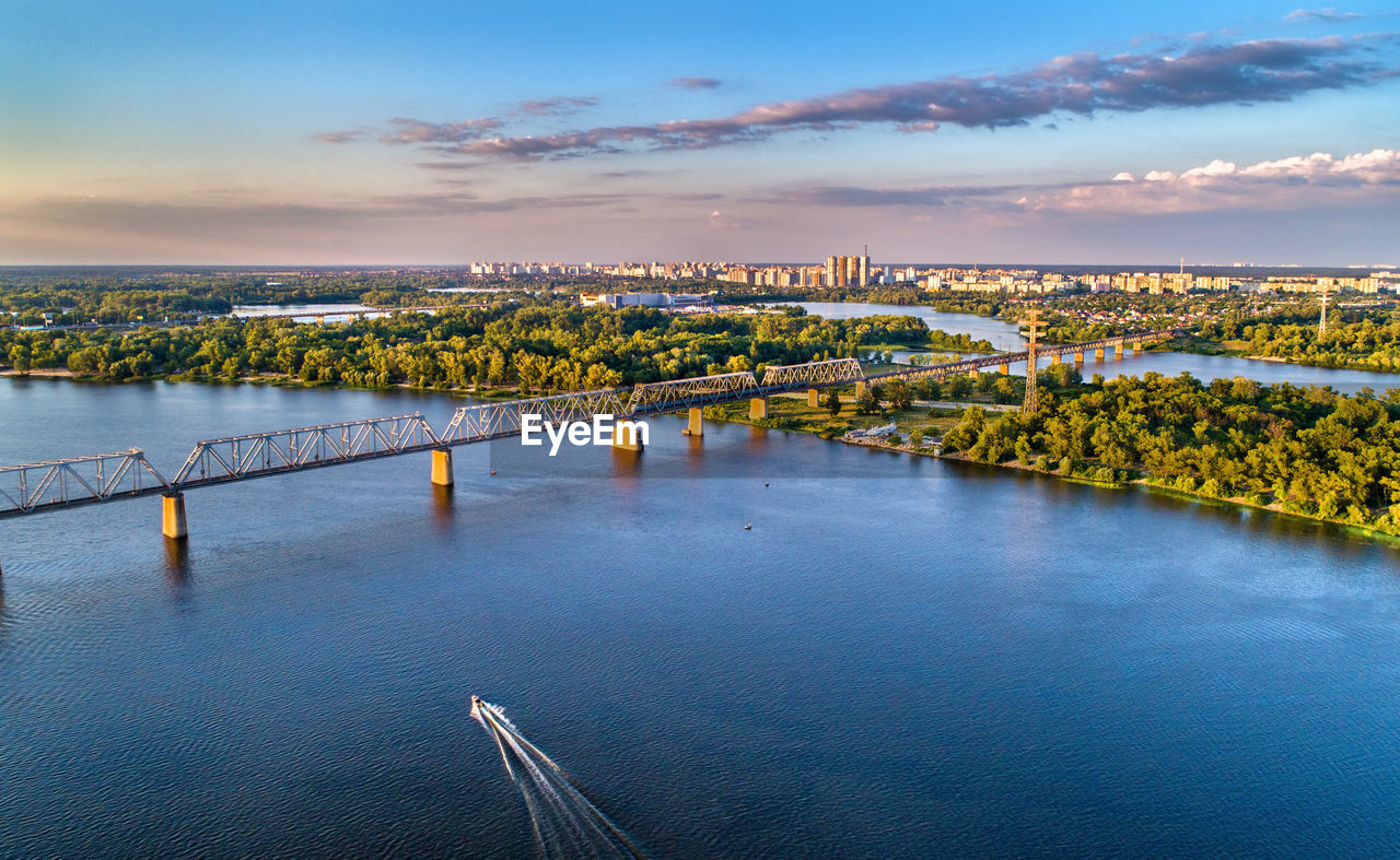 BRIDGE OVER RIVER BY CITYSCAPE AGAINST SKY