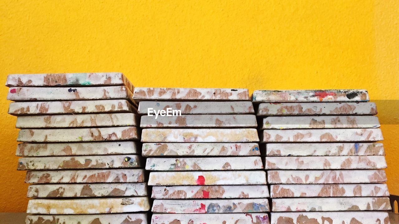 Stacked tiles against yellow wall