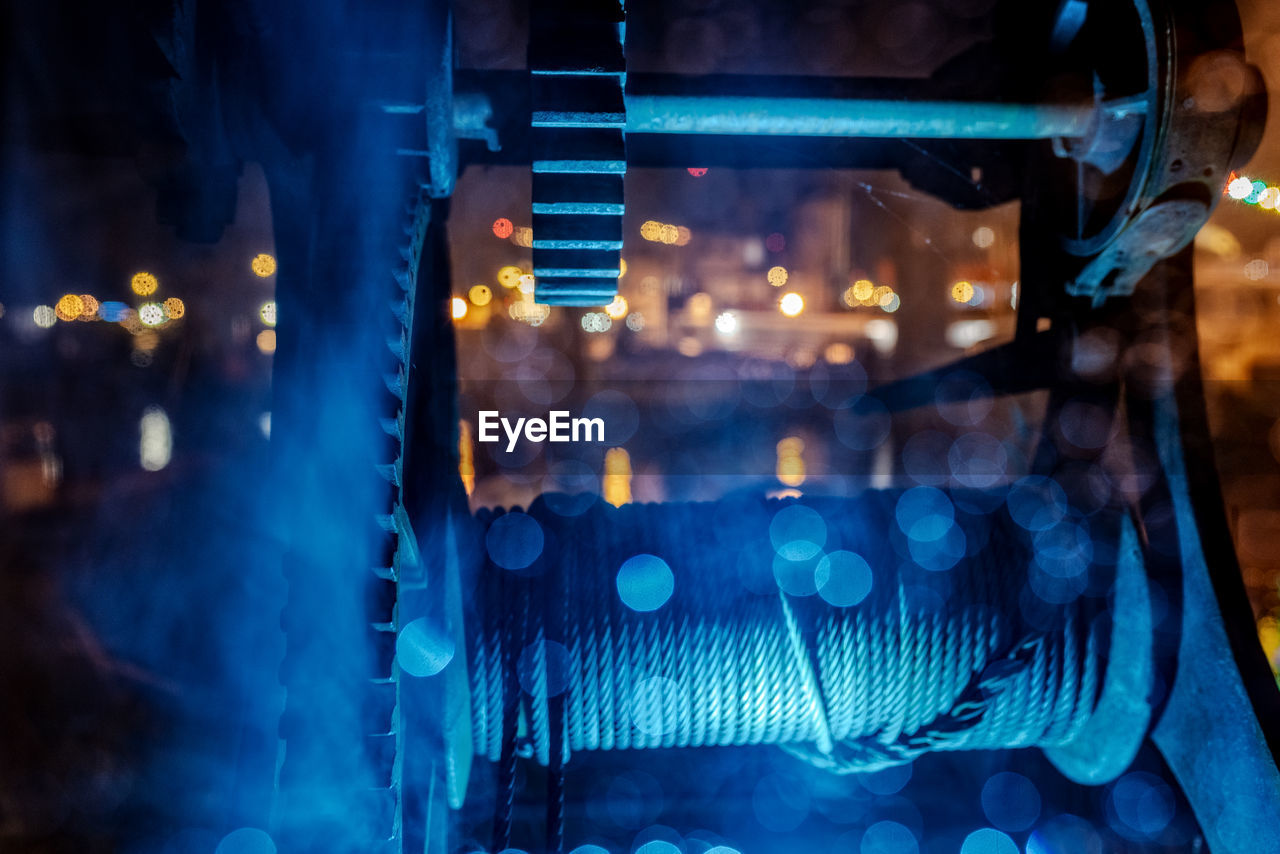 Close-up of pulley against illuminated lights at night