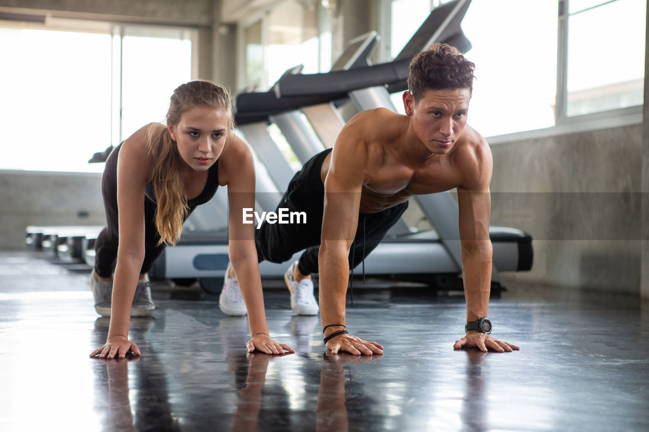 Friends doing push-ups on floor in gym