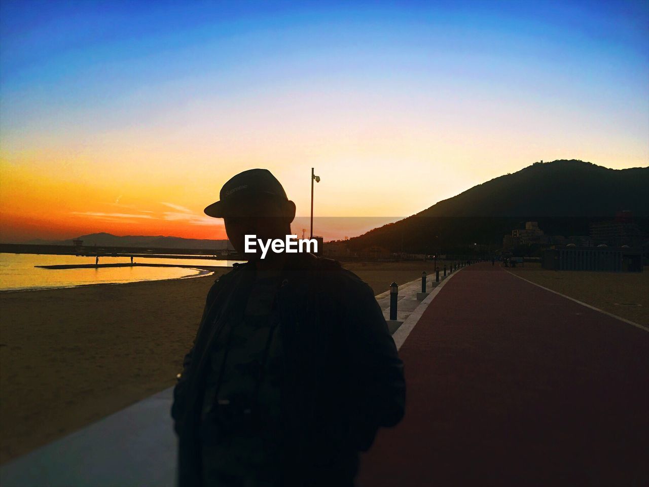 SILHOUETTE MAN STANDING ON BEACH AGAINST CLEAR SKY