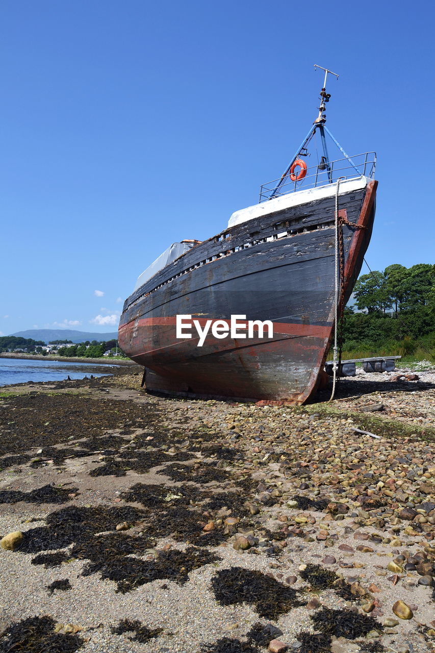 BOAT MOORED ON SHORE AGAINST CLEAR SKY