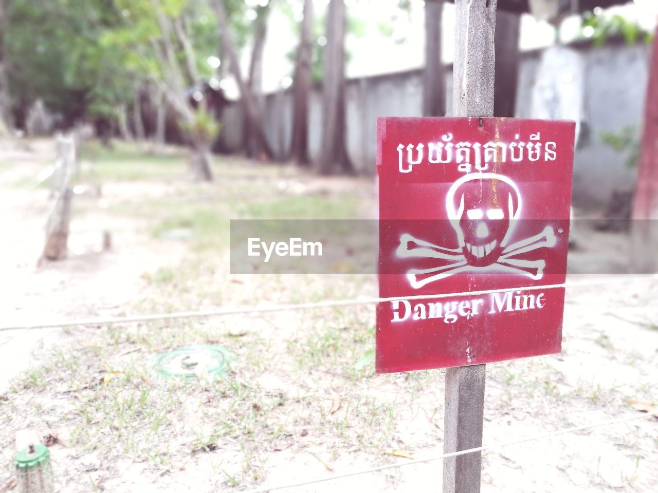 Land mine warning sign on pole at field