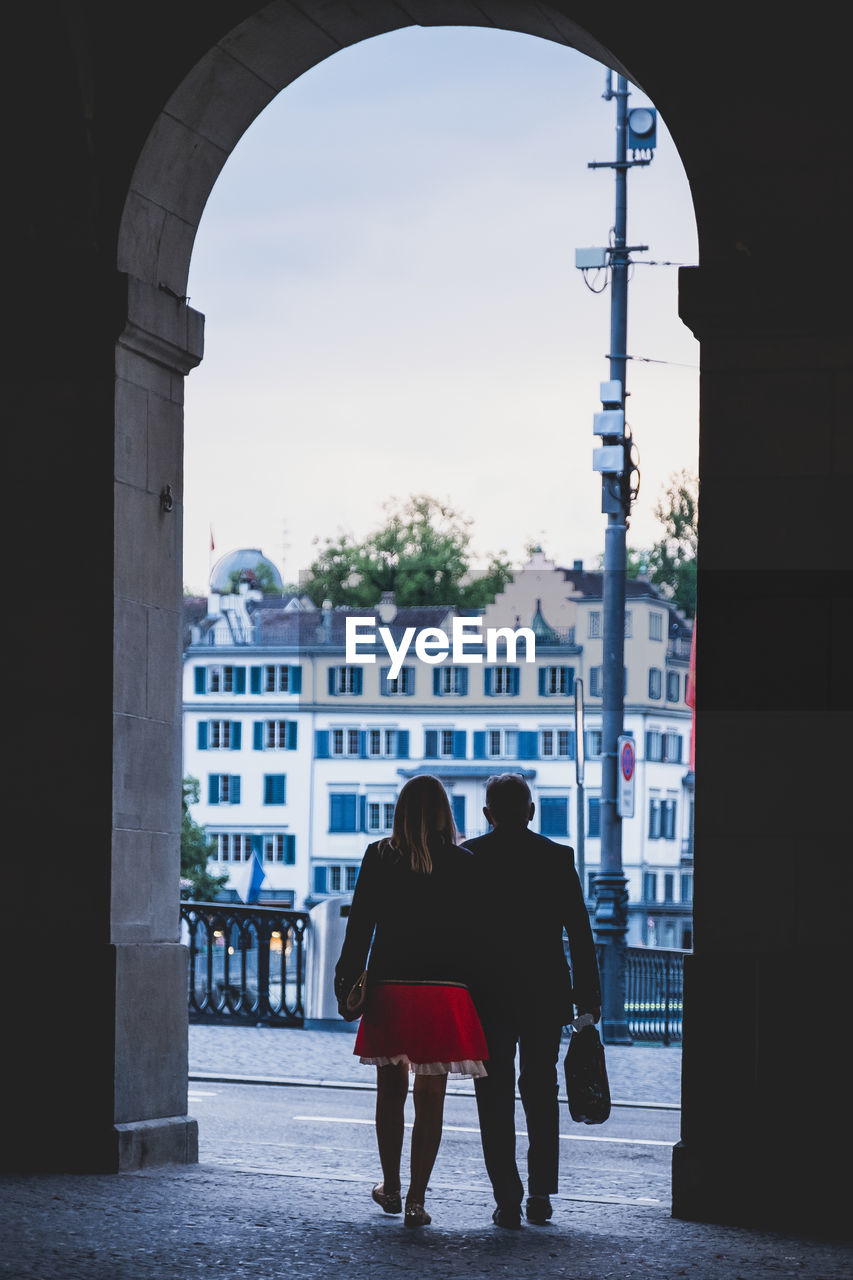 Rear view of man and woman walking through arch