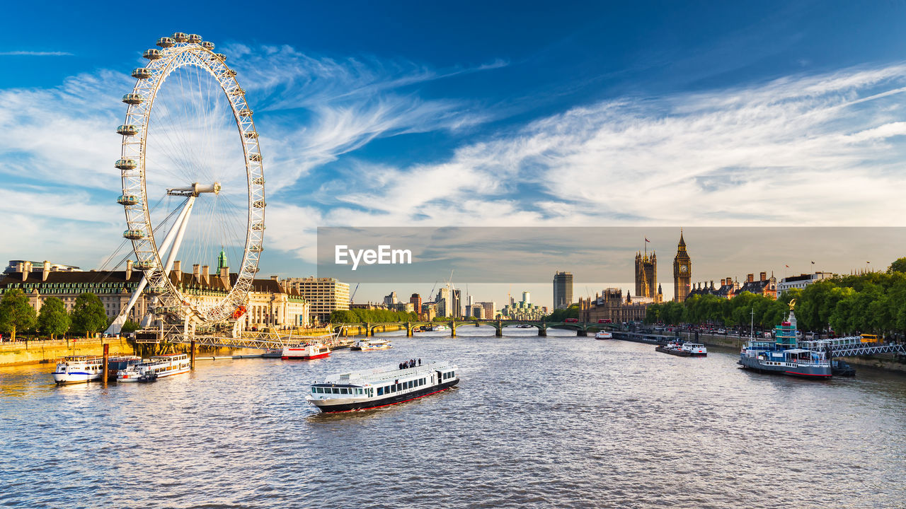 Ferris wheel by river in city