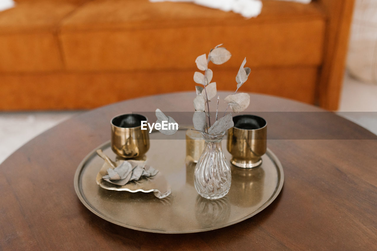 Gold glasses, dried flowers in a vase on a round tray on the coffee table