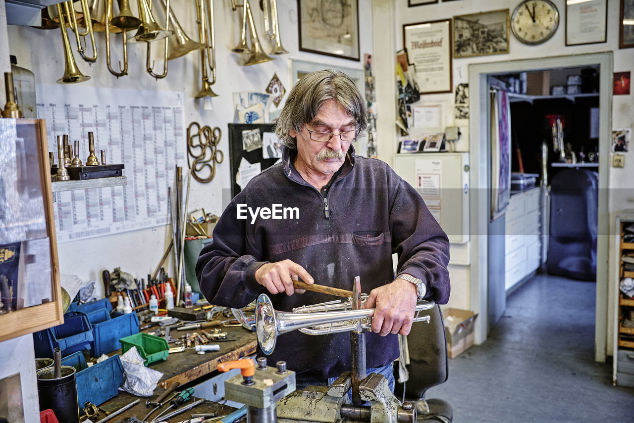 Instrument maker repairing trumpet in workshop