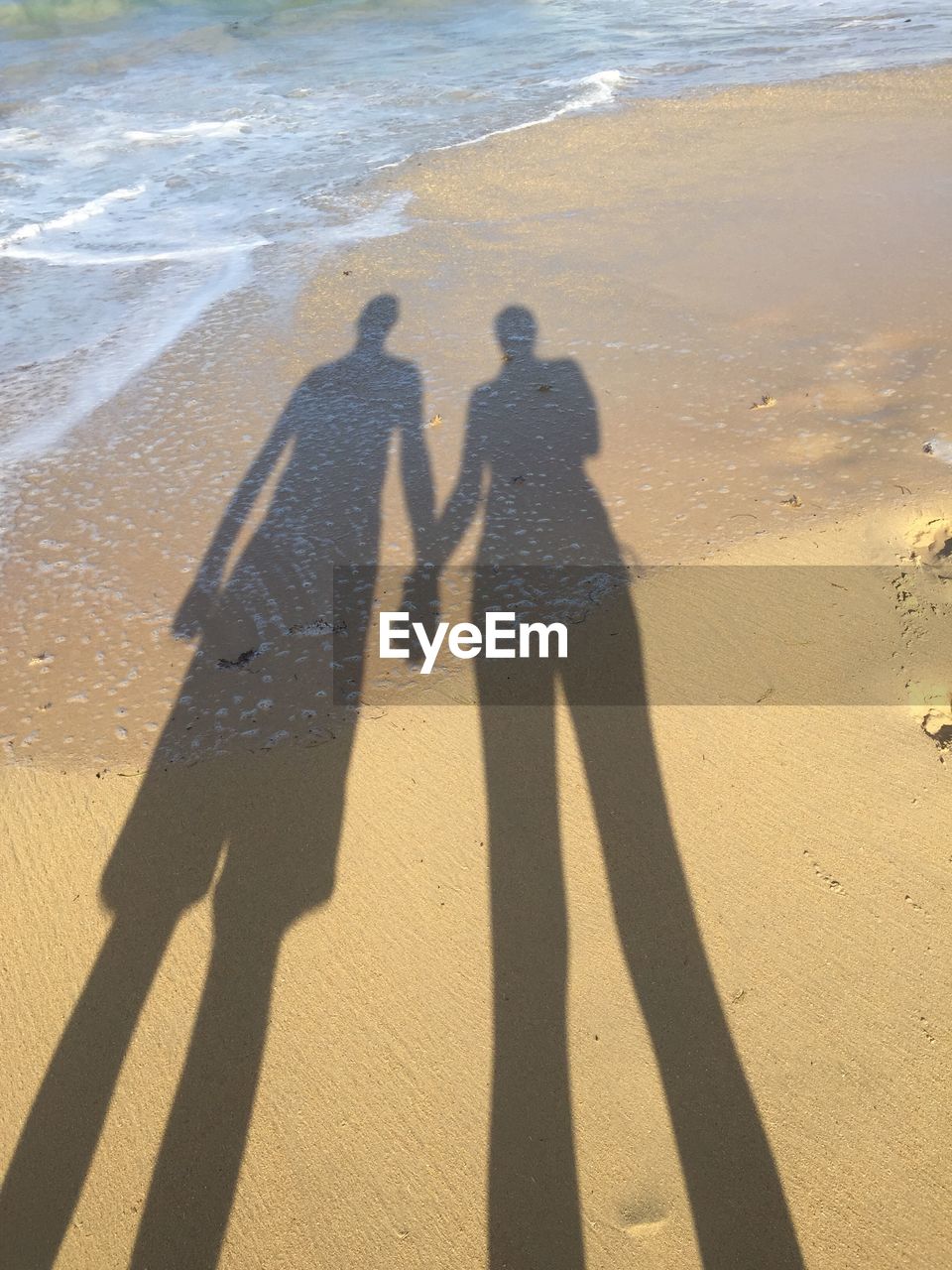 Shadow of people on sand at beach