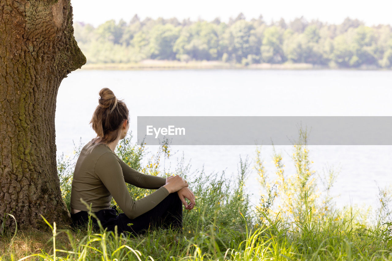 rear view of young woman sitting on field