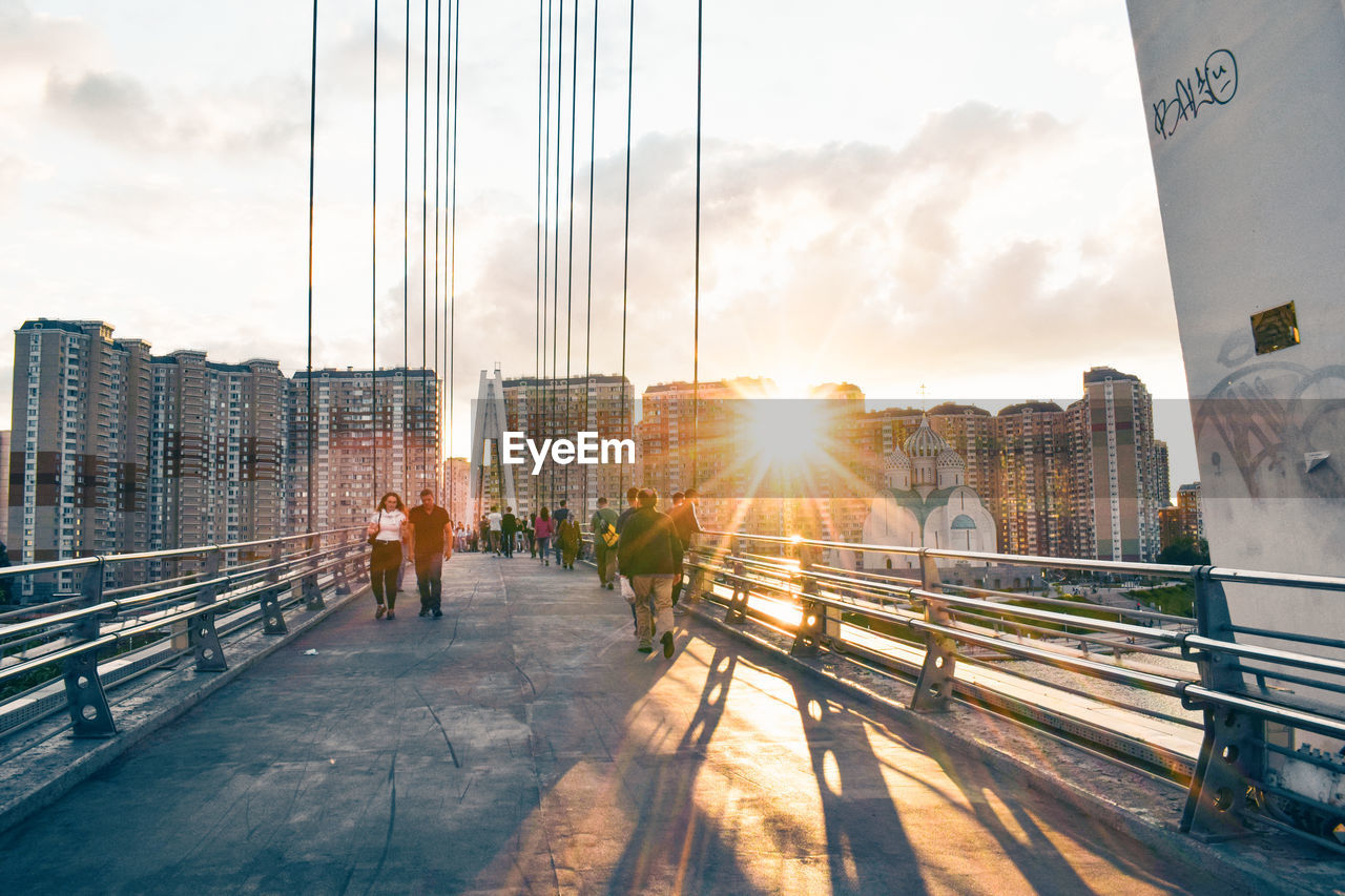 PEOPLE ON BRIDGE IN CITY AGAINST SKY