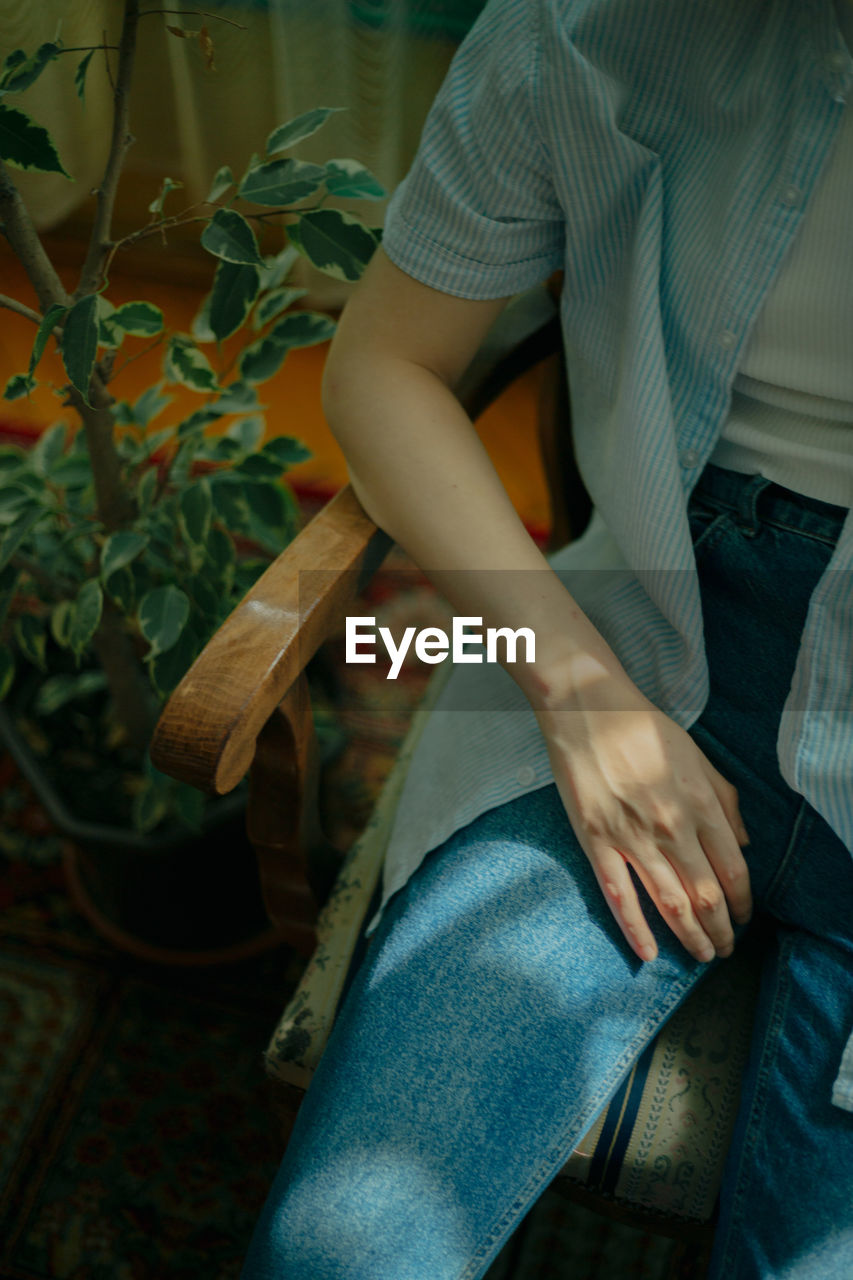 Midsection of woman sitting on chair at home