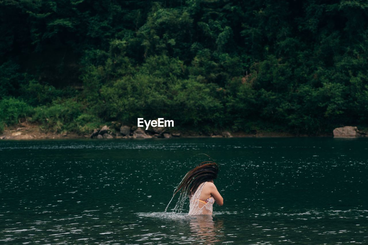 Woman tossing hair in lake 