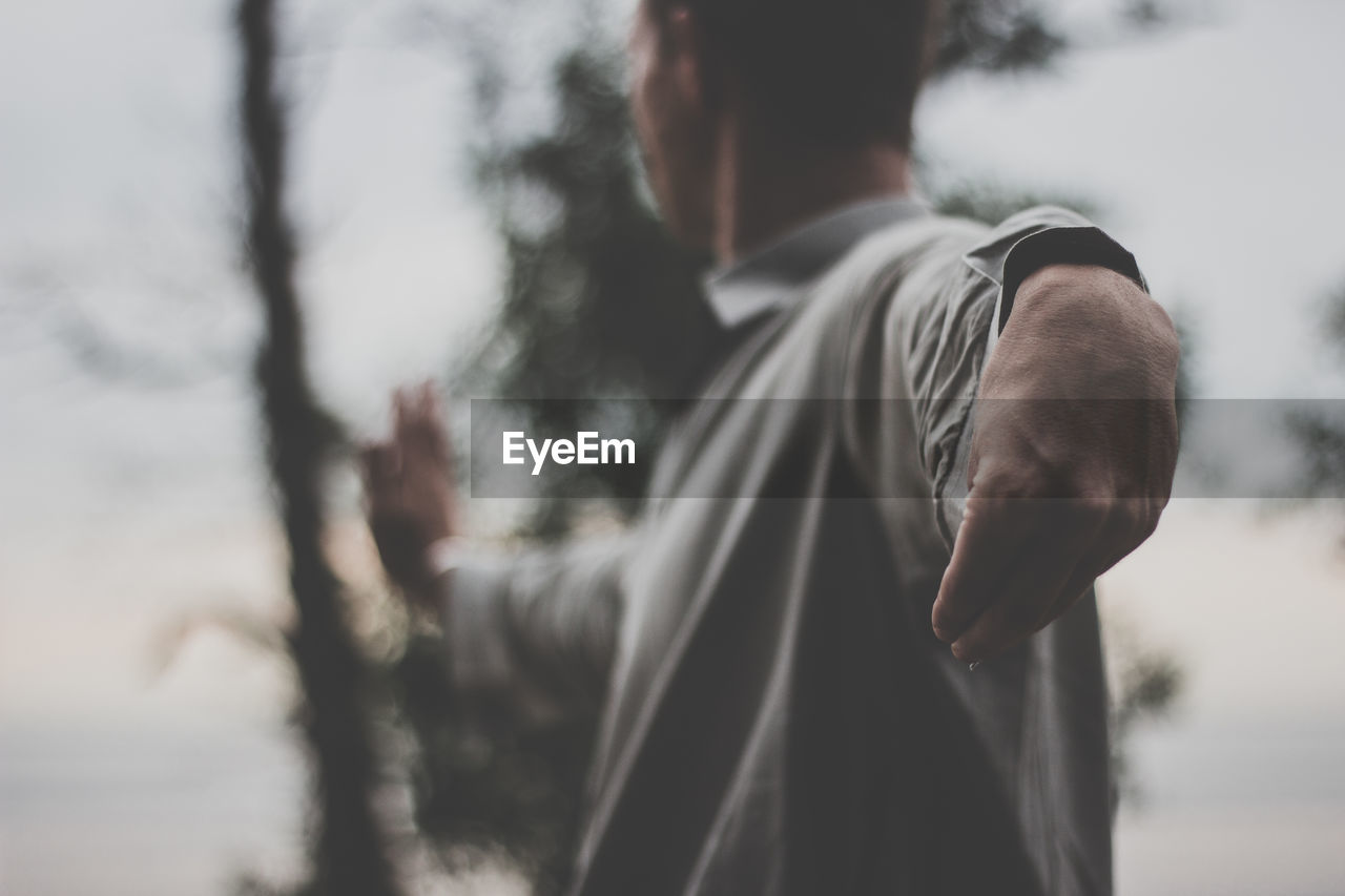 Midsection of man gesturing against sky