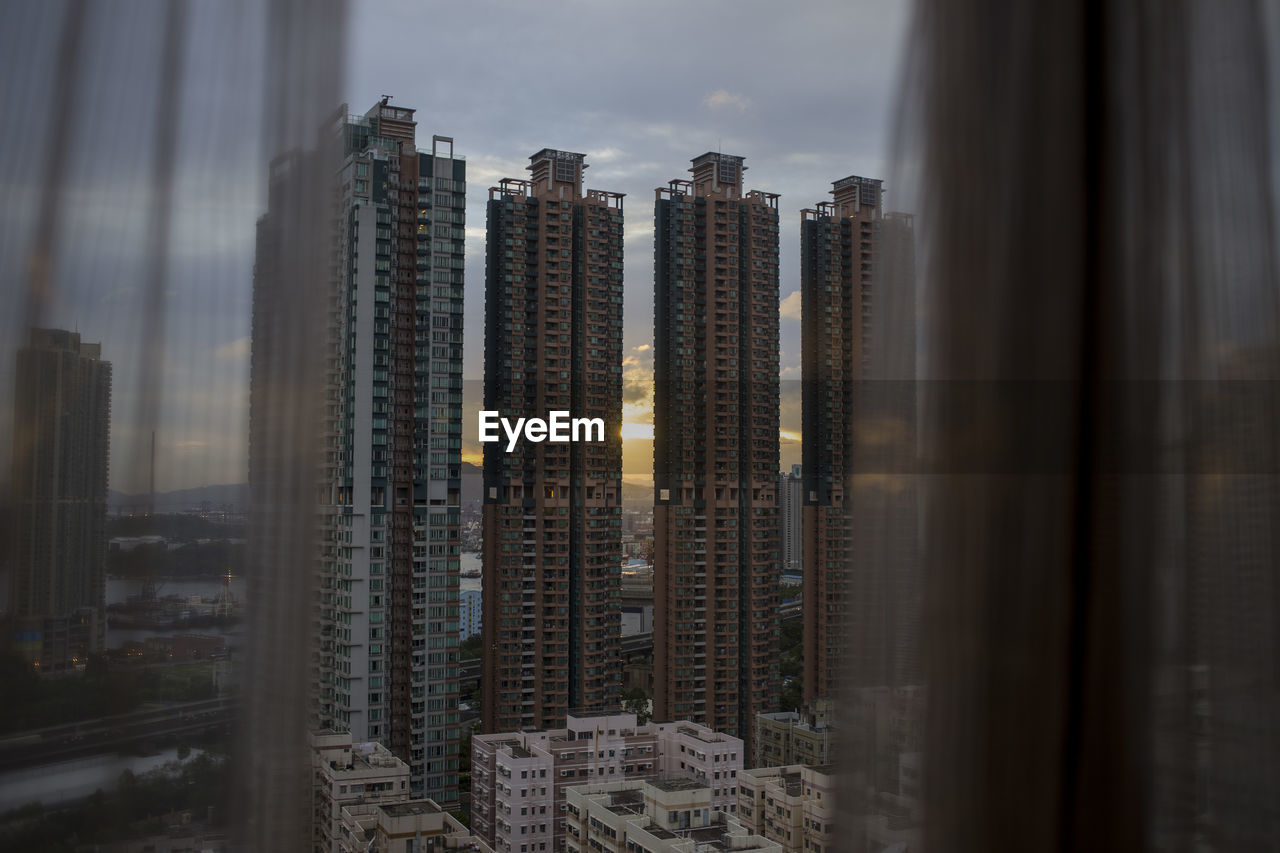 Modern buildings against sky seen through glass window, hong kong