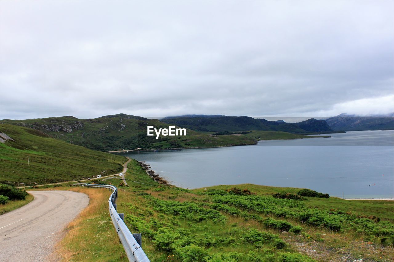 ROAD BY LAKE AGAINST SKY